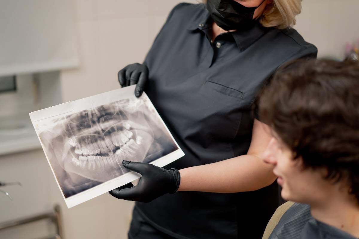 dental office blonde dentist in a black uniform consulting patient showing a photo of the teeth