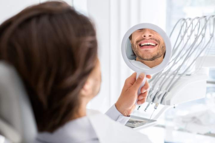 satisfied-patient-checking-smile-at-mirror-in-dent-2023-11-27-04-51-57-utc_720